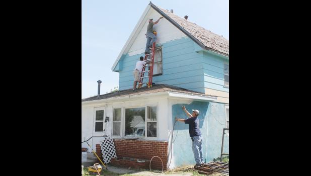 Some volunteers scraped off old paint, while others applied primer where needed, then painted the house yellow with brown trim.