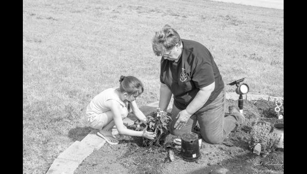 Jewell Bork helps Presley Geigle plant flowers in the planter. Bork played a major role in organizing the planter project. Photo by Barb Hockenbary Photography