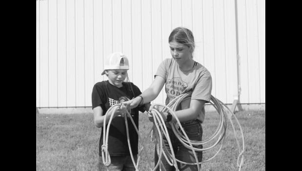 Grace Gesinger teaches Morgan Glassgow how to hold a lasso correctly. Photo by Mishayla Buchannan